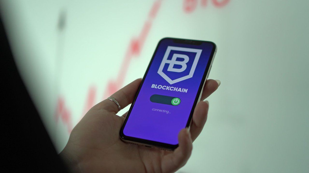 Mão segurando um smartphone com a tela de uma carteira de criptomoedas baseada em blockchain