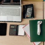 Mesa de escritório organizada com laptop, calculadora, terminal de pagamento e documentos.