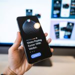 Mão segurando um smartphone com a interface de uma carteira digital na tela.